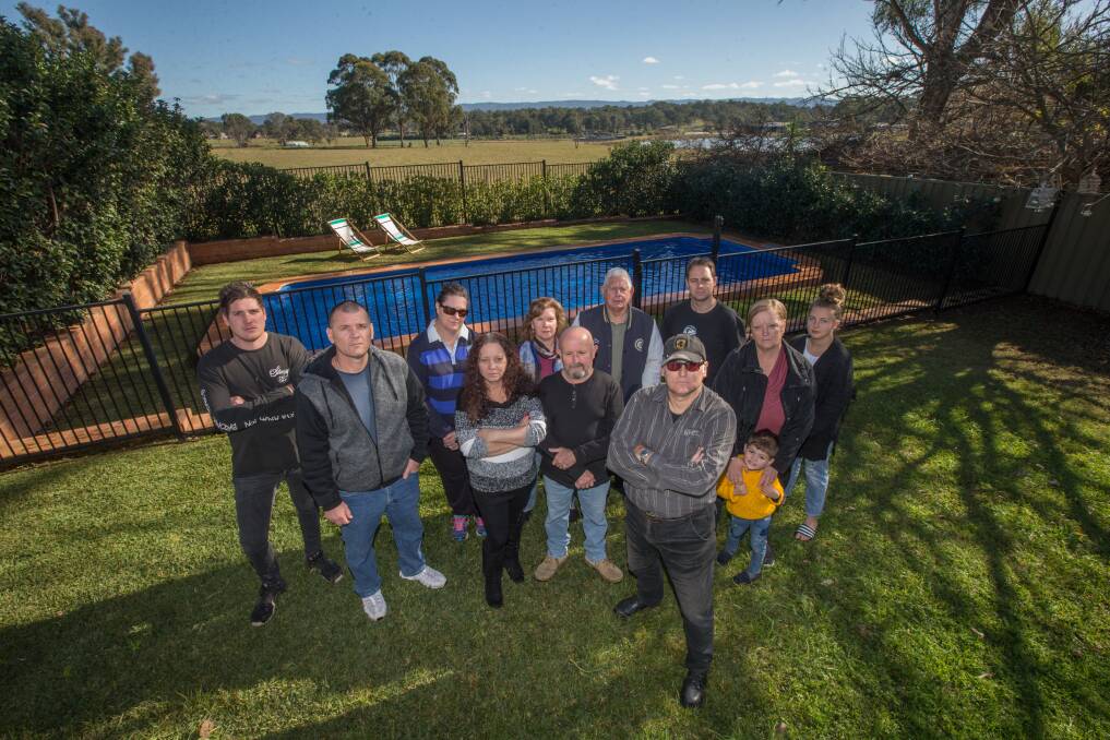 Maurice Geake, front right, in his backyard with neighbours including Shayne Ryan, Ian and Linda Shepherd and Trish Corbett, who have objected to the proposed intensive flower farm next to their properties at Freemans Reach. The farm land is visible behind the pool fence. Picture: Geoff Jones