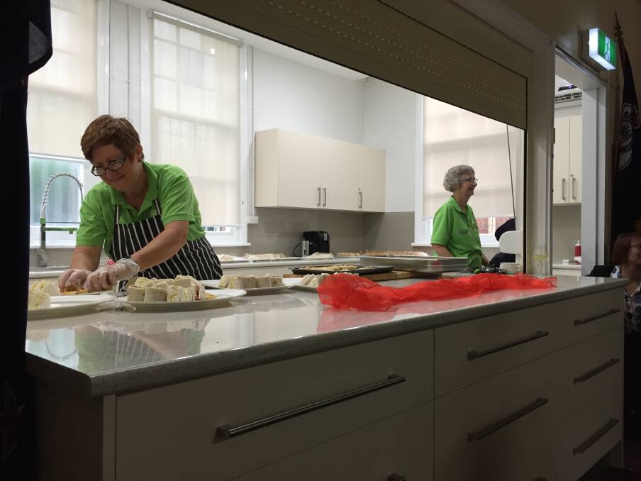 Volunteer Tracey Kelleher, left, makes good use of the new kitchen, creating a delicious repast of hot and cold finger food for the celebratory lunch.