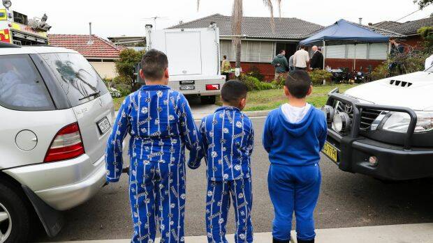 Children watch as police search a house on Pollock Street, Georges Hall.  Photo: Janie Barrett