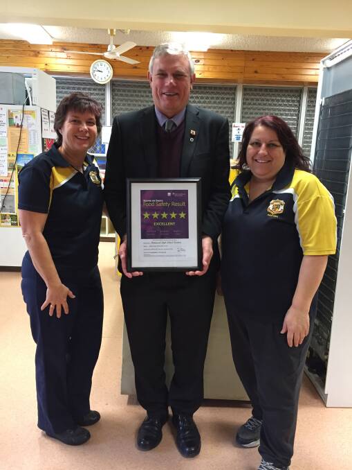 Principal Clifford Ralph with Cathy James and Annette Cessar showing their five-star food safety certificate.