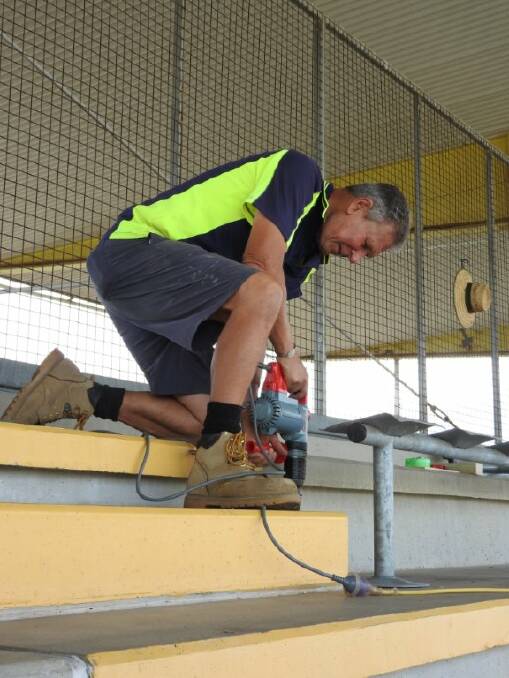 HARD YAKKA: Phil Close, one of the Showground Committee members, drilling the first hole to install the seats from Parramatta Stadium.