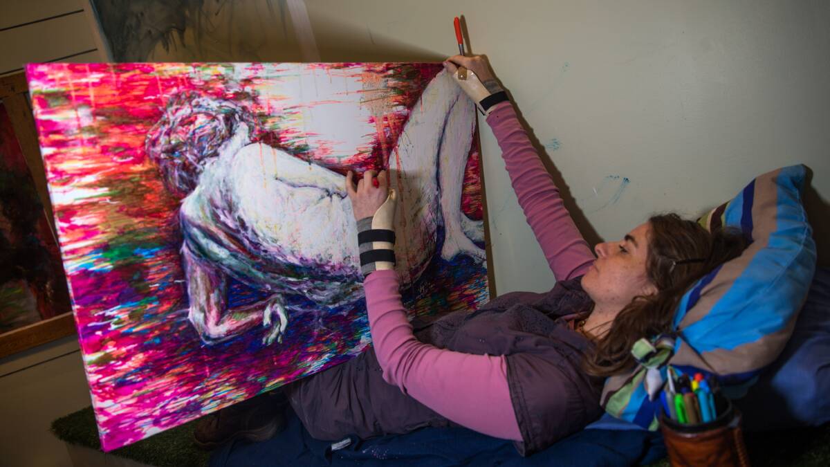 DOING HER THING: Ms Hyett sometimes has to lie down to paint, in order to ease the pressure on her back. Picture: Geoff Jones