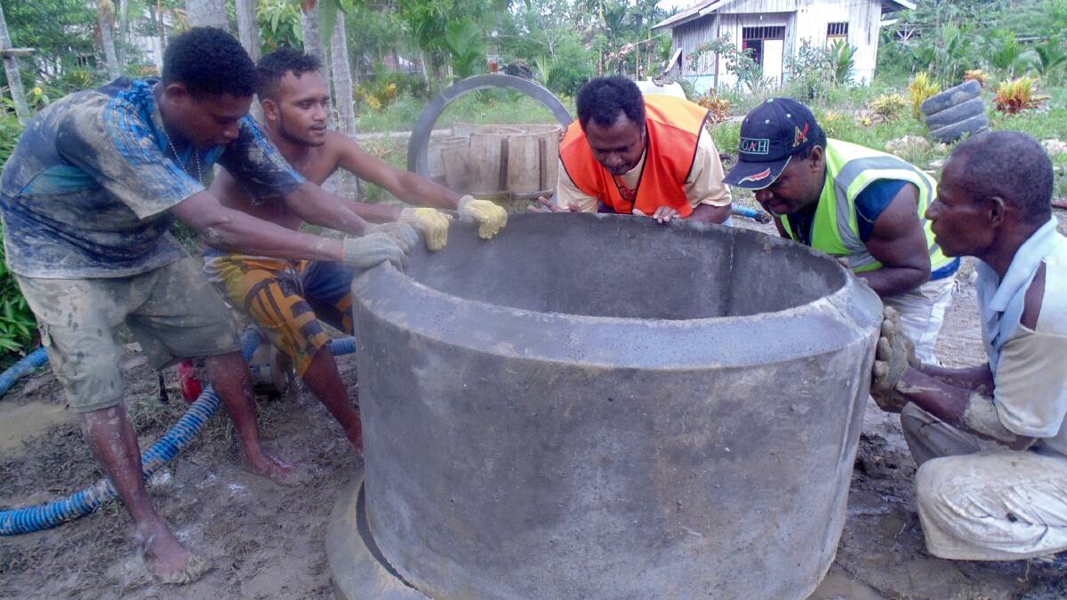 Many hands: Workers put in place a collar for a new water well.