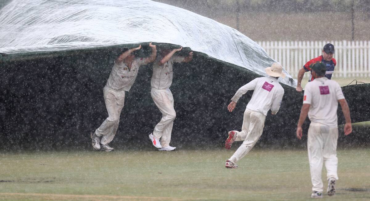 Players rushed to get the covers on at Owen Earle Oval on Saturday during the second grade match between Mosman. Picture: Geoff Jones