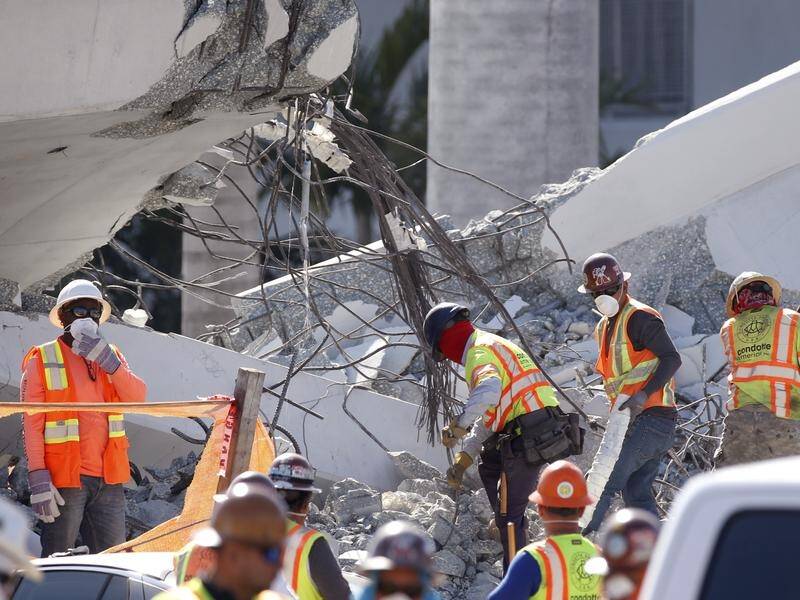 Workers are slowly removing the debris of a pedestrian bridge that collapsed in Miami, killing six.