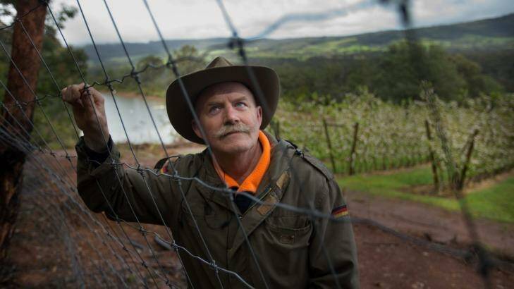 Kevin Sanders at one of the fences he built to keep deer out of his apple orchard. Photo: Simon Schluter