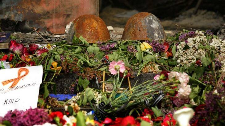 Charred remains: Two burnt police helmets among flowers left at the entrance of the police station in Mariupol. Photo: Kate Geraghty