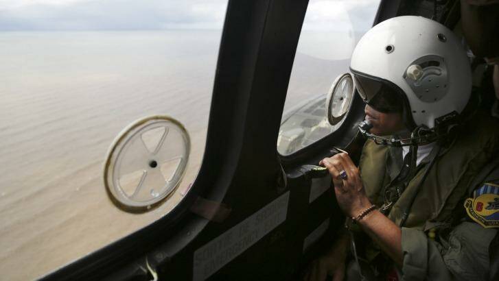 A crew member of an Indonesian Air Force Super Puma helicopter looks out a window  during a search operation for the crashed AirAsia Flight 8501 over the Java Sea.