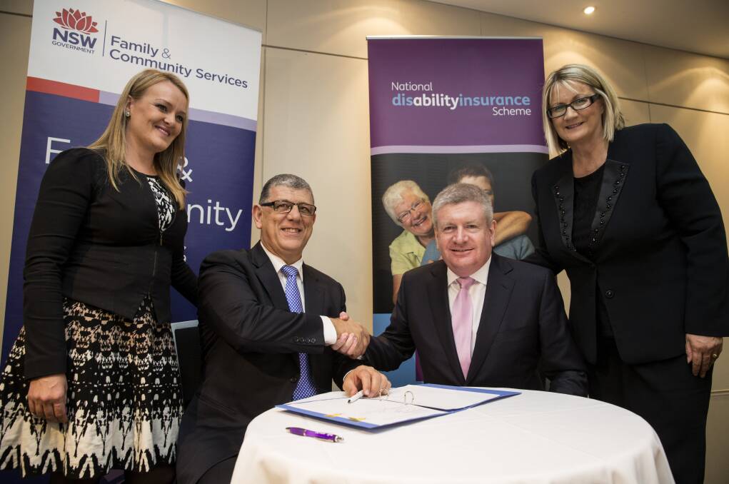 Signed, sealed and now to deliver: Macquarie MP Louise Markus (far right) watches as the NDIS agreement is signed by John Ajaka and Mitch Fifield in Penrith on Tuesday. Picture: Geoff Jones