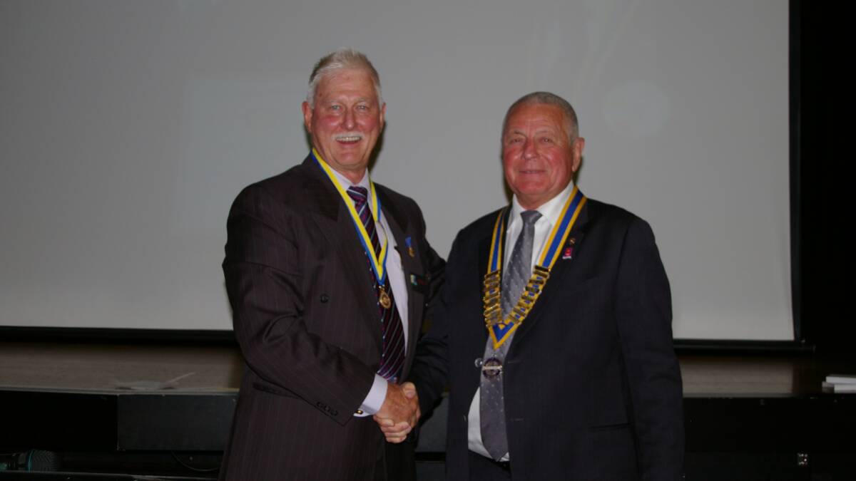 Retiring Windsor Rotary president Laurie Ross congratulates incoming president John Gollan.