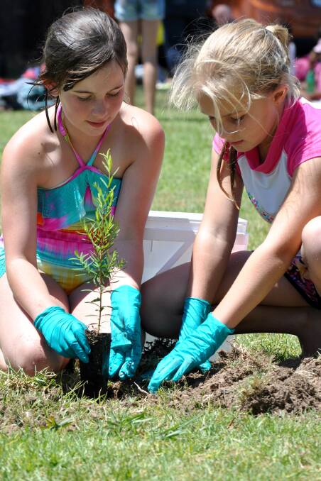 Leah Jones and Lily Ingersole, both 9, plant a tree.