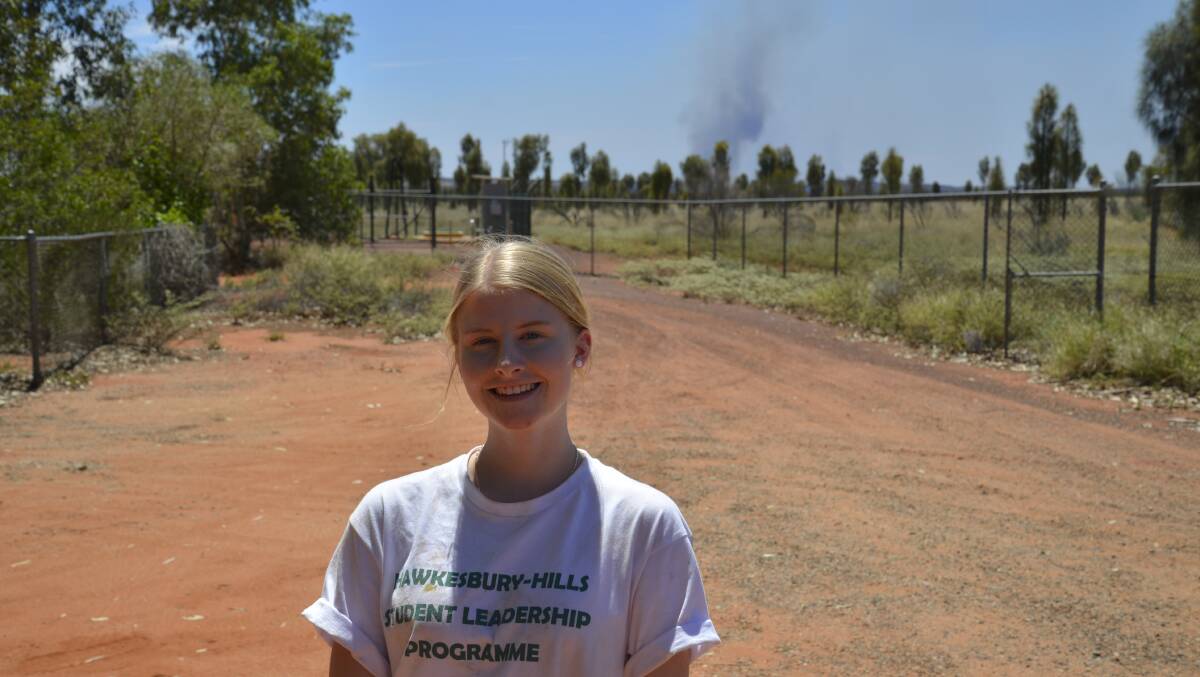 Hawkesbury High School's Megan Bradburn, pictured with a still burning fire from a lightning strike in the background, said she was nervous about coming on the trip, but in the end found it enjoyable. Picture: Conor Hickey
