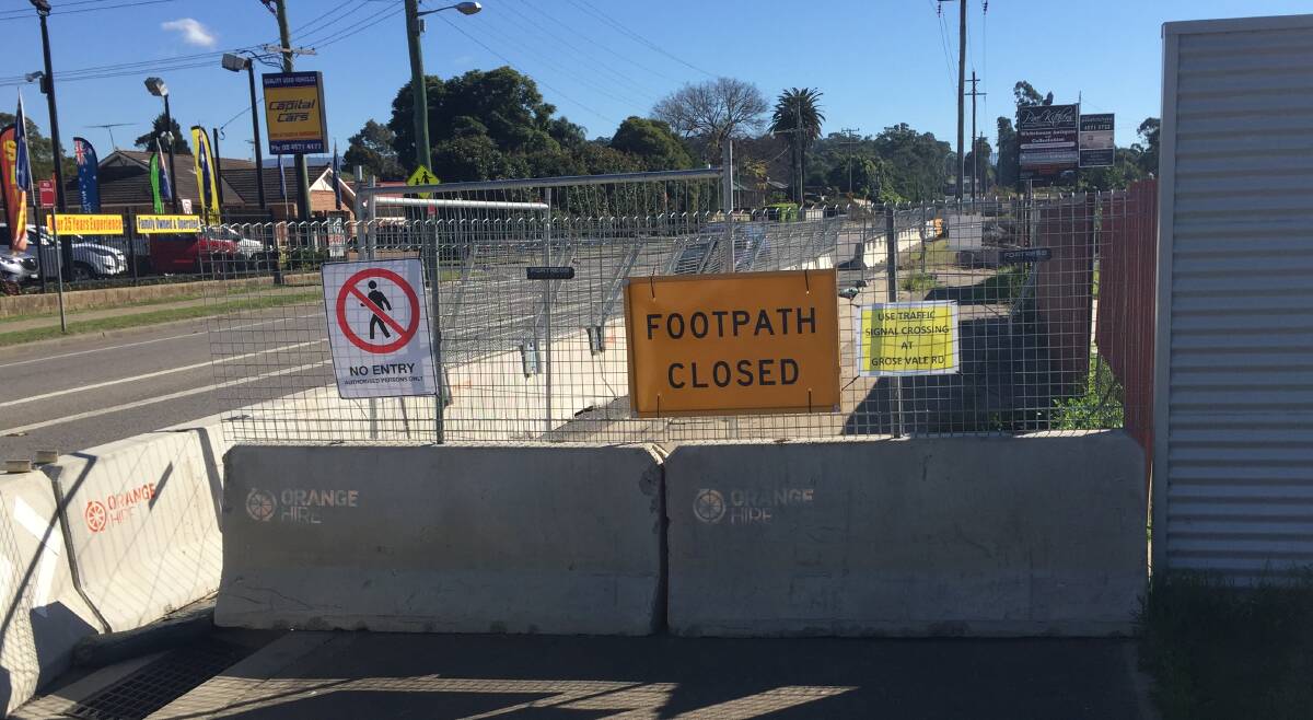 The construction site blocks the footpath, with this 'footpath closed' sign. A smaller sign urges pedestrians to use the lights at Grose Vale Road to cross.
