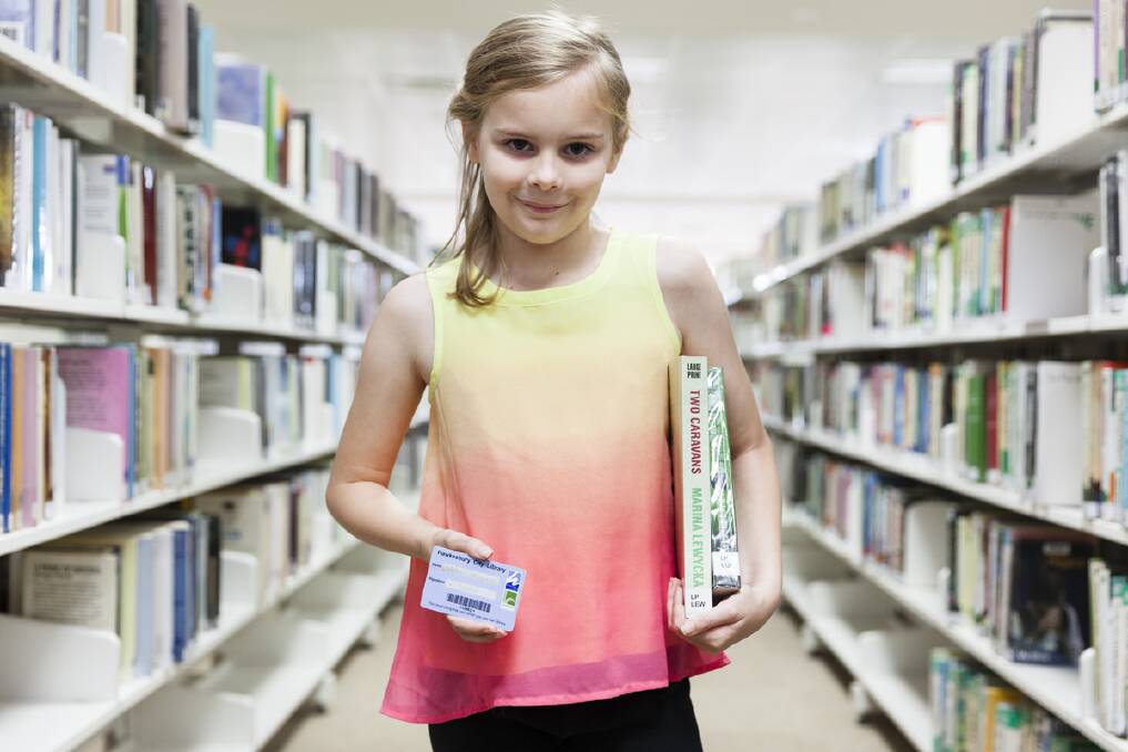 A young library goer with her library card and books.