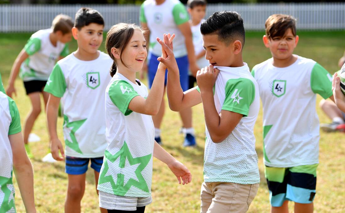 Having fun: A pair of young league stars share a high-five during a session of the popular introductory rugby league program for kids. Picture: Gregg Porteous