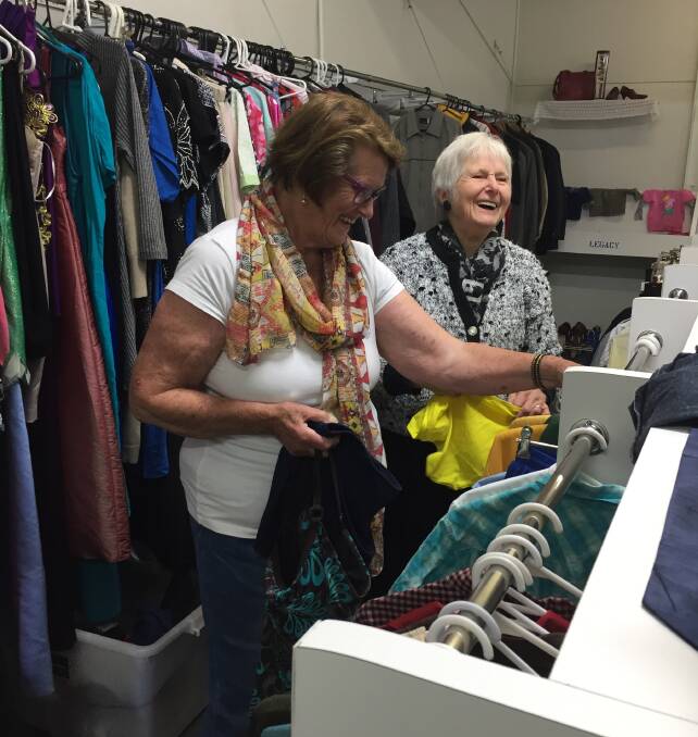 Volunteers Joan Chalk and Joyce Marshall enjoy a laugh with the customers while they unpack. 