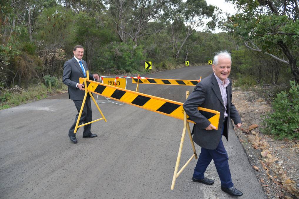 
Mayor Philip Ruddock (right) removes the barriers to open the road, with help from Berowra MP Julian Leeser.