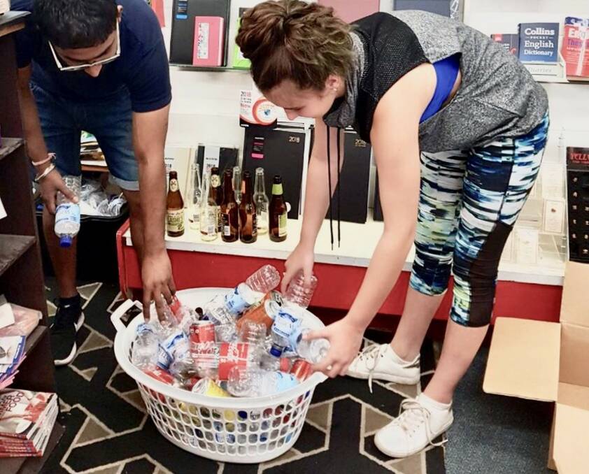 Kiera Braund, 12, of Freemans Reach brings in a basket of drink bottles and cans to Windsor Newsagency's Sumit Kumar last week. He has found the new scheme to be working well for him, though it's labour intensive.