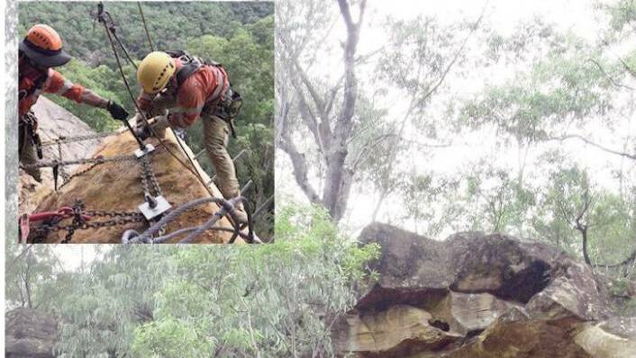 Specialist crews work to secure the boulder above the rail line at Glenbrook.