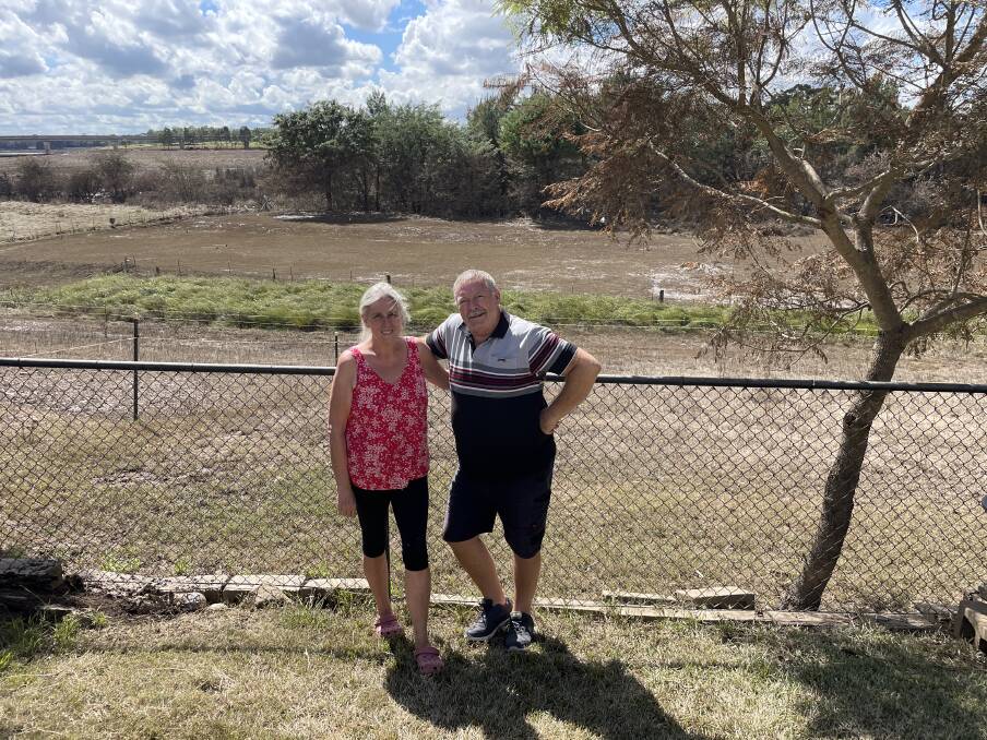 Sue and Steve Smith in their backyard, with South Creek behind them, which is where the water rose from. The flood reached 13.8 metres high, covering the entire area behind them and most of the tree that stands next to them. Picture: Sarah Falson