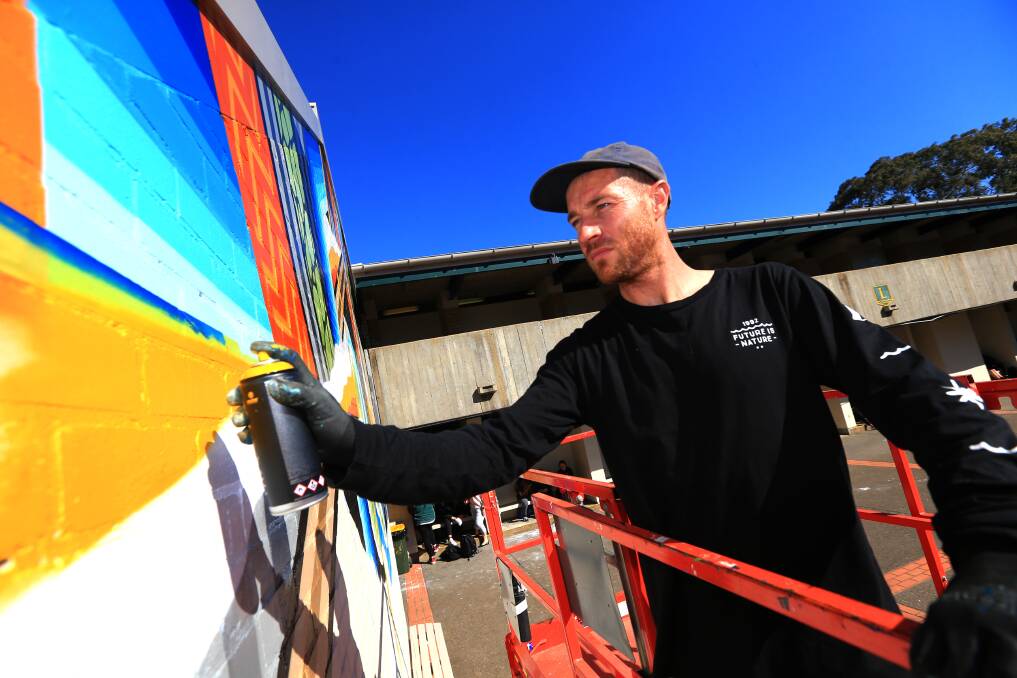 Artist Bradley Eastman AKA Beastman working on his mural in the quad at Windsor High School. Picture: Geoff Jones