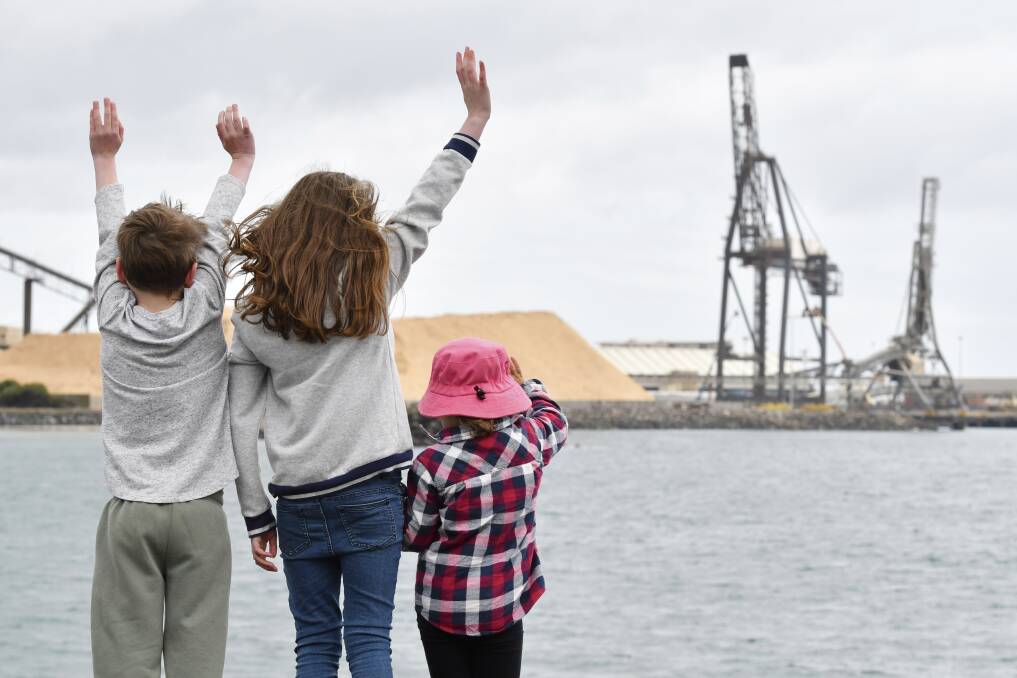 FAREWELL: Seth, 7, and Zara Hawkins, 9, of Devonport and Charlotte Richards, 4, of Sunnyside wave goodbye to the iconic Burnie portainer crane. Picture: Brodie Weeding