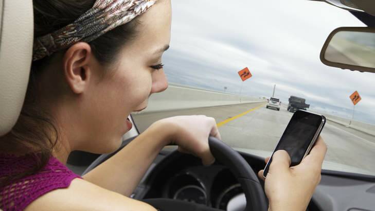 Driver distraction ... while it is illegal to drive and text, the Australian Mobile Telecommunications Association says hands-free mobiles used in cradles are legal. Photo: istock photos
