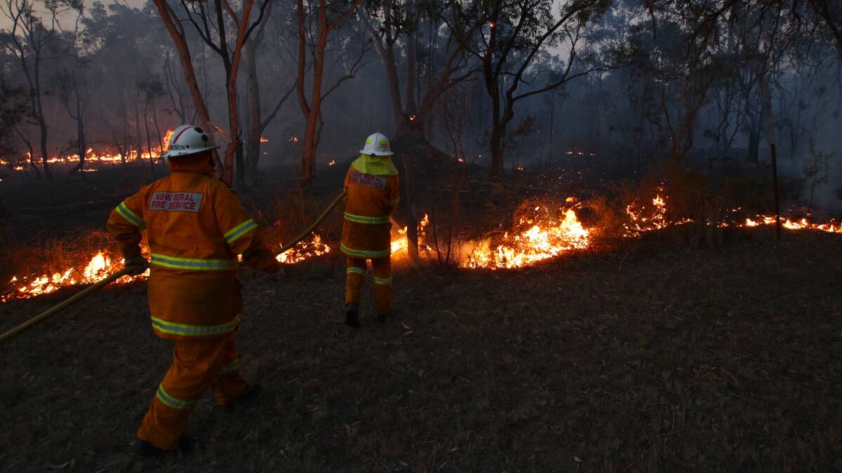 Rural Fire Service crews from Sutherland and Loftus keep an eye on the flank of a bushfire near Londonderry. Photo: DALLAS KILPONEN